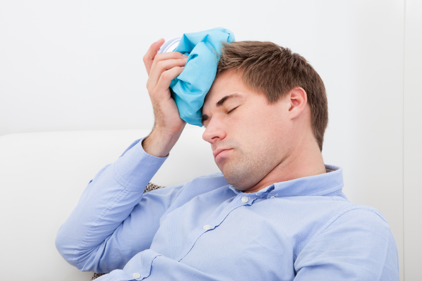Young Man Suffering With Headache Applying Icepack