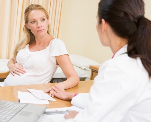 Doctor with laptop and pregnant woman in doctor's office